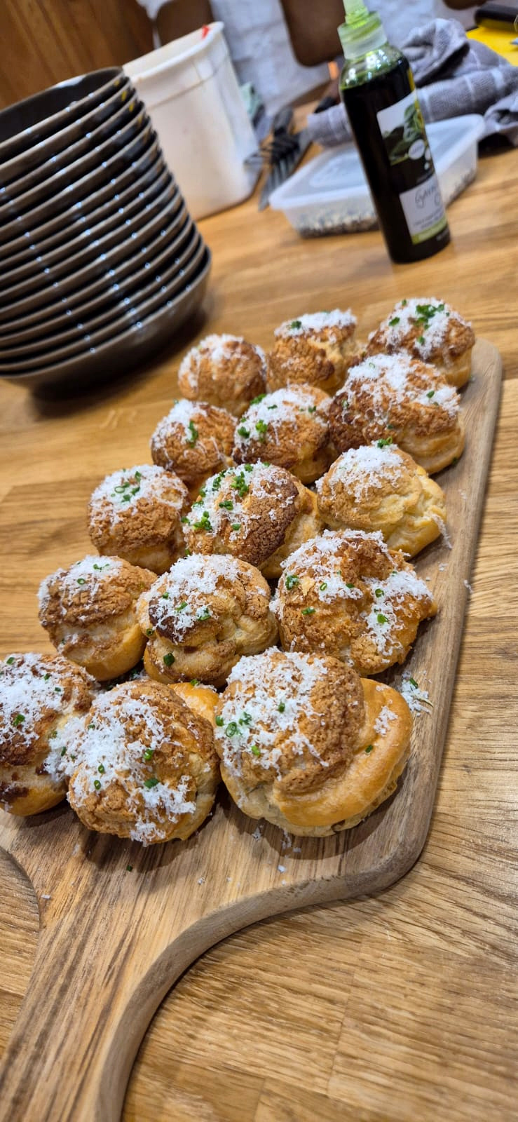 Gougères dusted with parmesan and chives on a wooden board